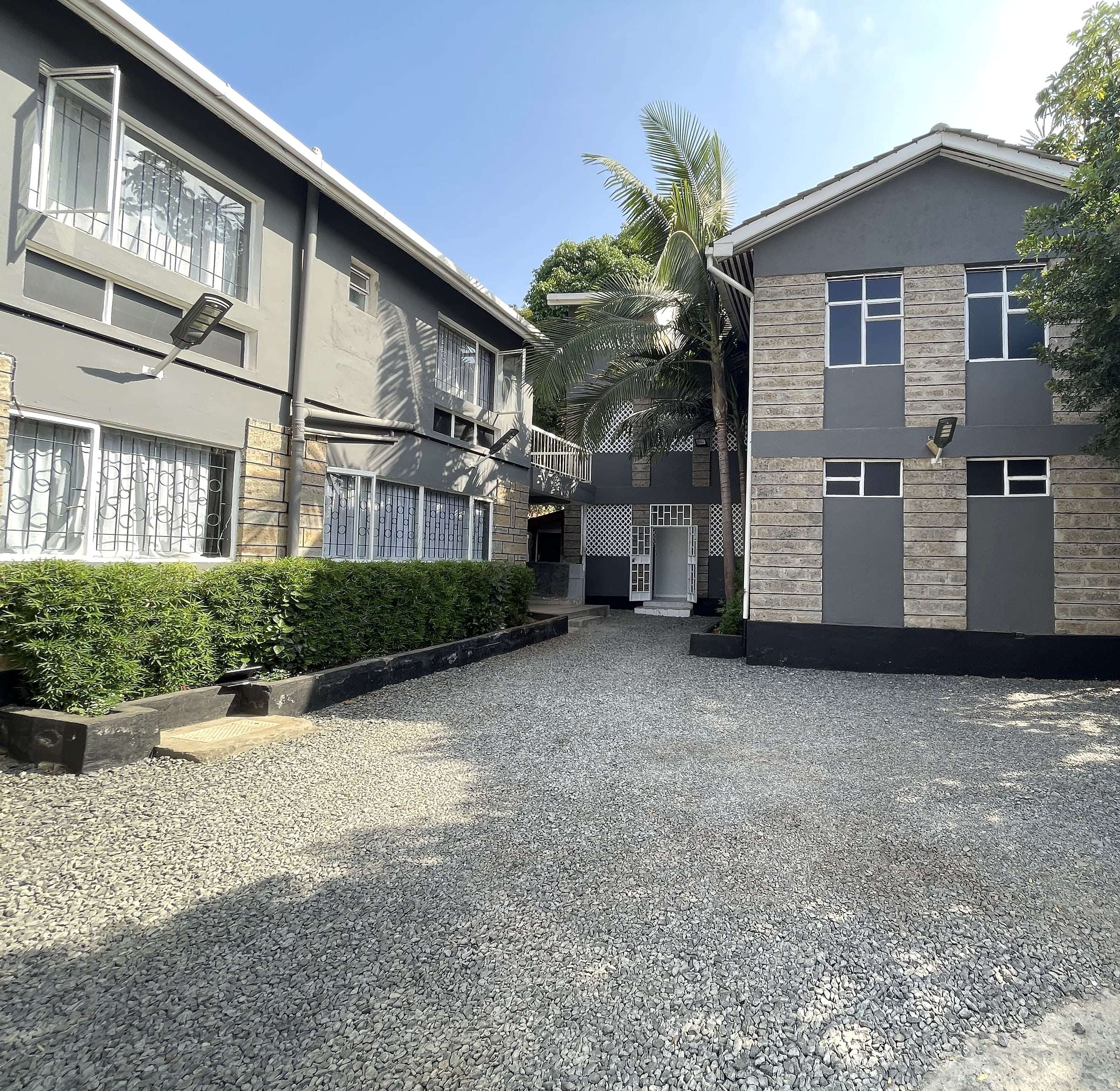 Maskan Guest House buildings behind neat hedges inside the compound