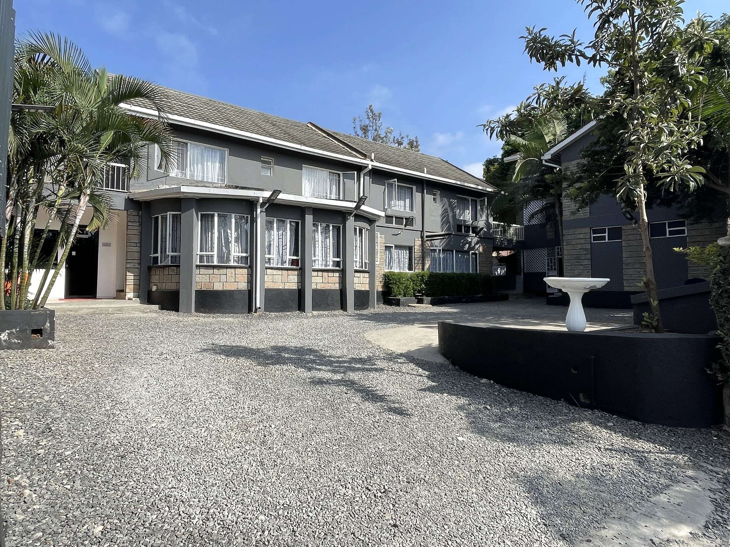 The gated courtyard with ample gravel parking, palms and a birdbath