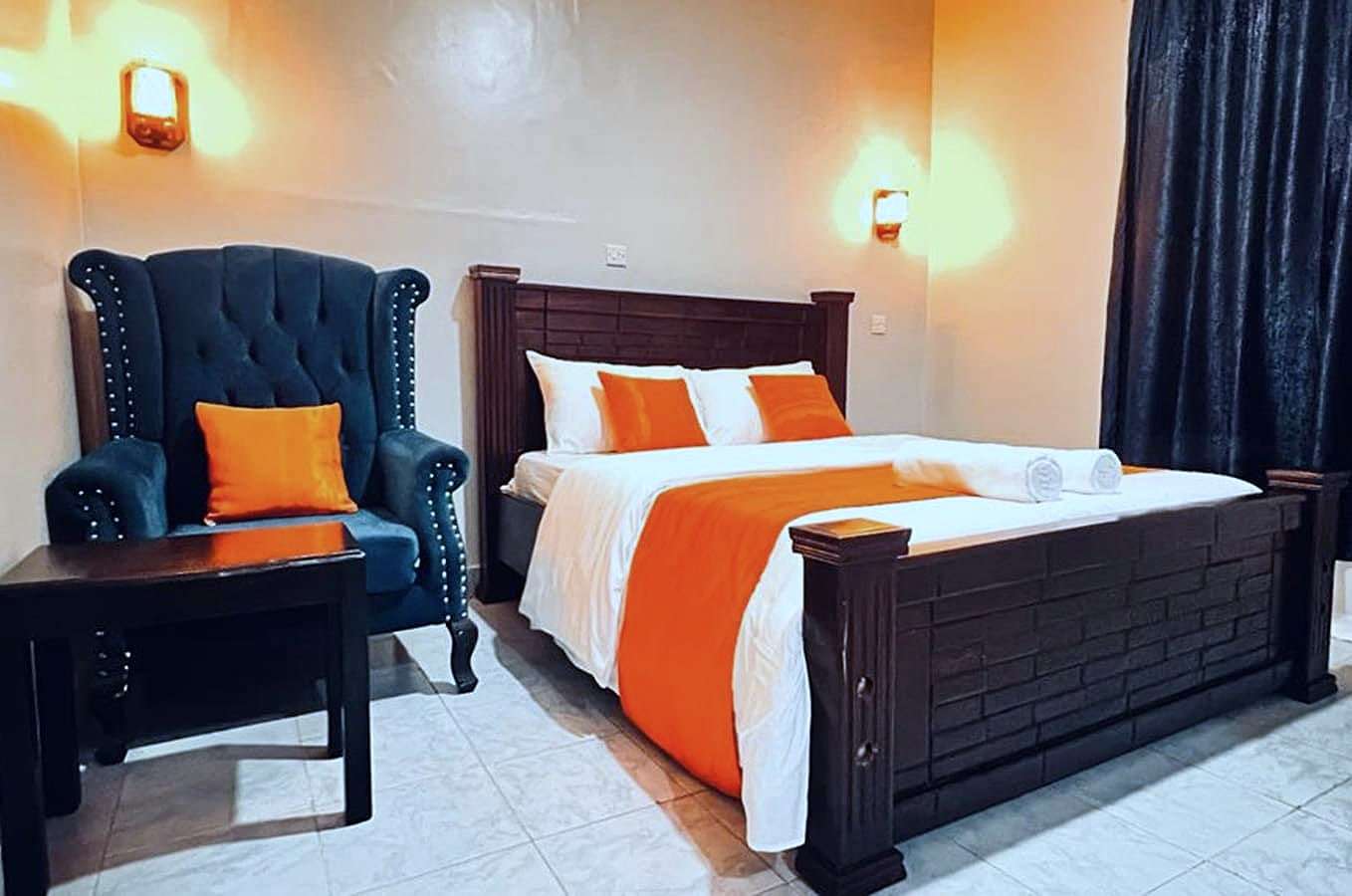 Superior room with a carved wooden bed and a blue wingback armchair