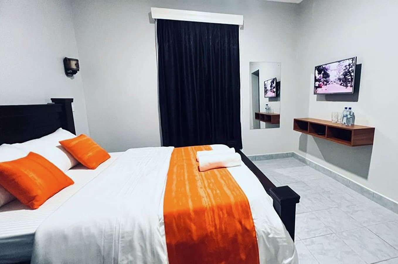 Superior room bed with white linen and an orange throw