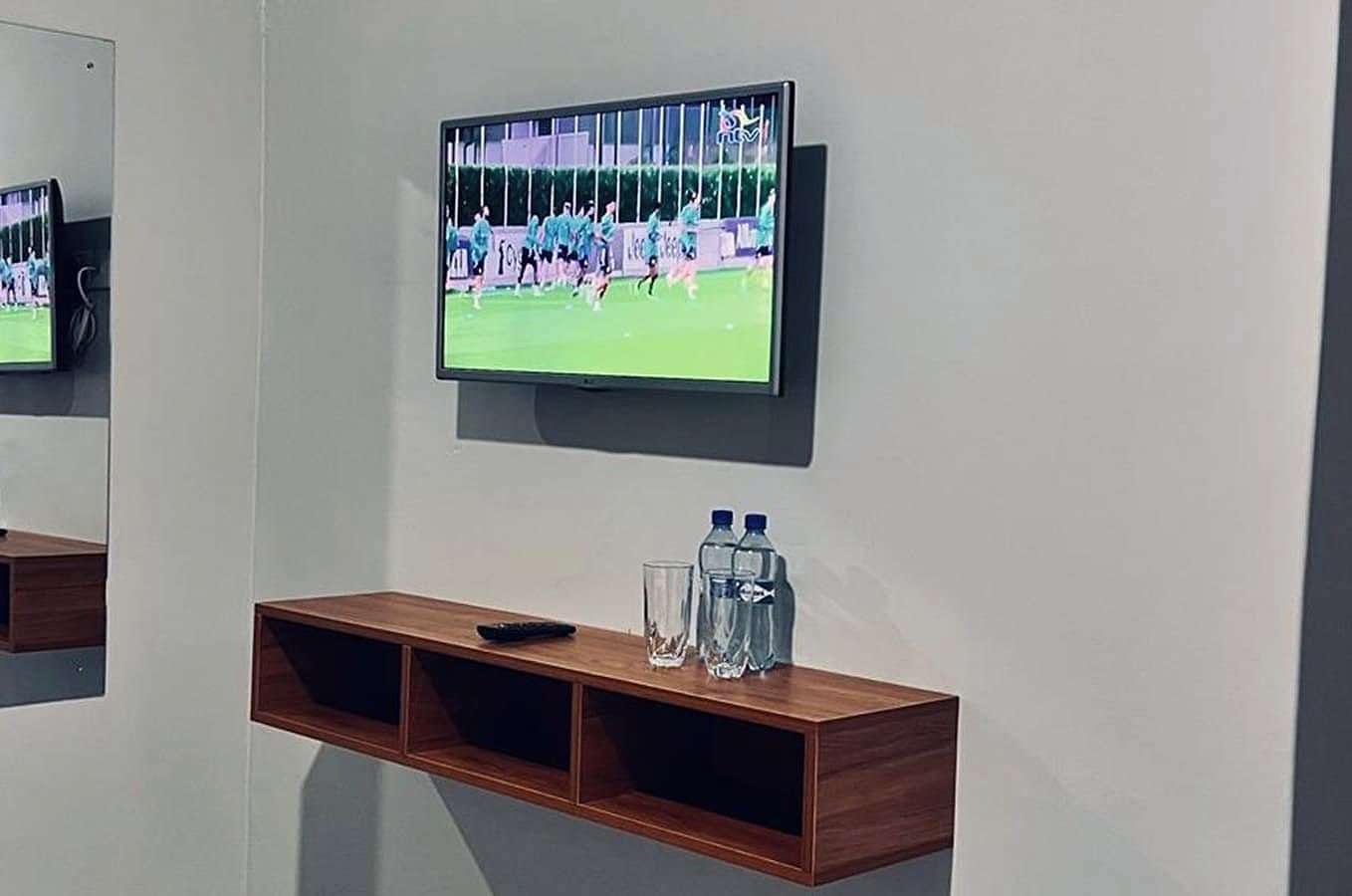 Wall-mounted smart TV above a floating wooden shelf