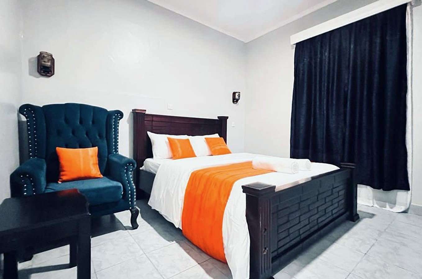 Superior room with armchair, wooden bed and blackout curtains